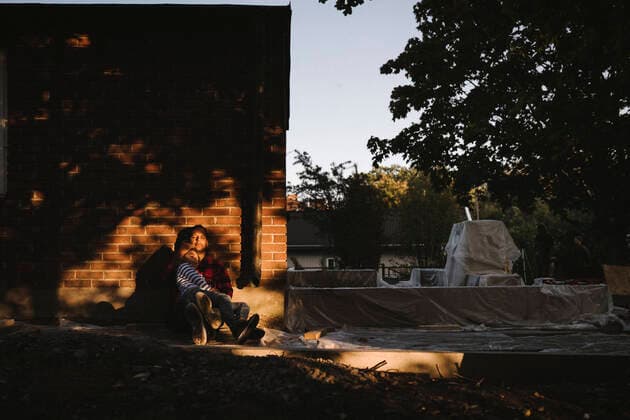 IMAGO Creative: Landleben - Alfresco, Draußen Son resting on father s lap against house during sunset Sweden, Stockholm, model released, property released Copyright: xMaskotx , MA83102