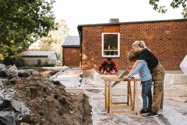 Mother and son using hand saw while father with daughter by concrete wall against house Sweden, Stockholm, model released, property released Copyright: xMaskotx , MA83111