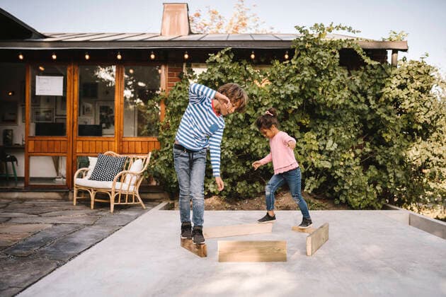 Playful siblings balancing on wooden planks against house Sweden, Stockholm, model released, property released Copyright: xMaskotx , MA83179