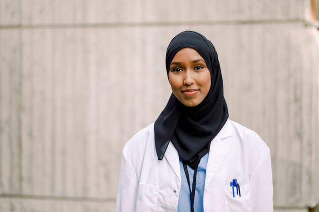 Portrait of smiling nurse wearing hijab while standing against wall in hospital Sweden, Stockholm, model released, property released Copyright: xMaskotx , MA83319