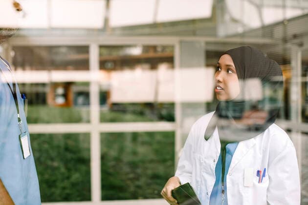 Young female nurse talking to colleague in hospital seen through glass window Sweden, Stockholm, model released, property released Copyright: xMaskotx , MA83325