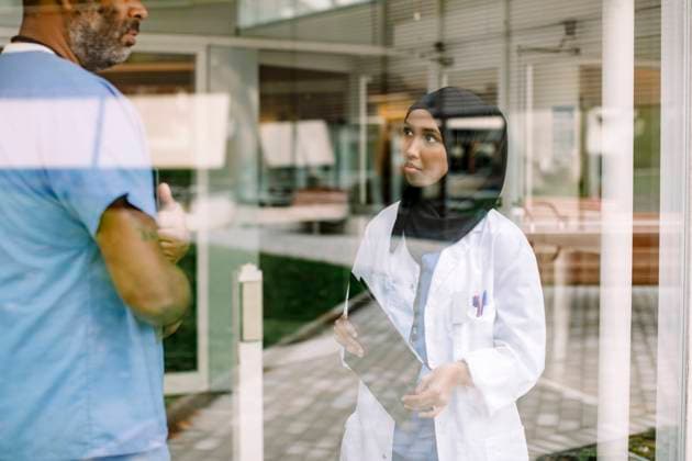 Young female nurse talking to colleague in hospital seen through glass window Sweden, Stockholm, model released, property released Copyright: xMaskotx , MA83327