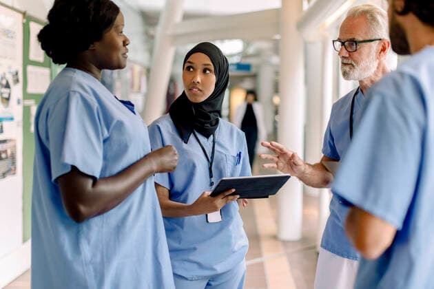 Confident senior male and female nurses talking in hospital corridor Sweden, Stockholm, model released, property released Copyright: xMaskotx , MA83355