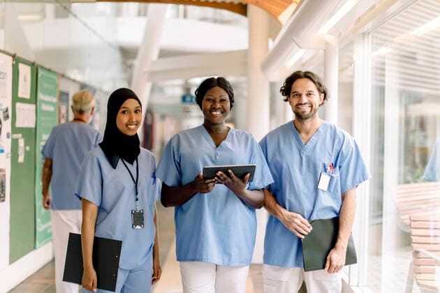 Portrait of smiling female nurse with digital tablet by colleagues in hospital Sweden, Stockholm, model released, property released Copyright: xMaskotx , MA83359
