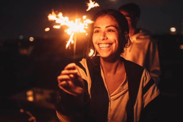 Cheerful woman looking at igniting sprinkler on rooftop at night Germany, Berlin, model released, property released Copyright: xMaskotx , MA83569