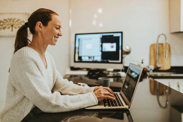 Woman on video call with friend through laptop at kitchen island model released Symbolfoto property released DMGF00347