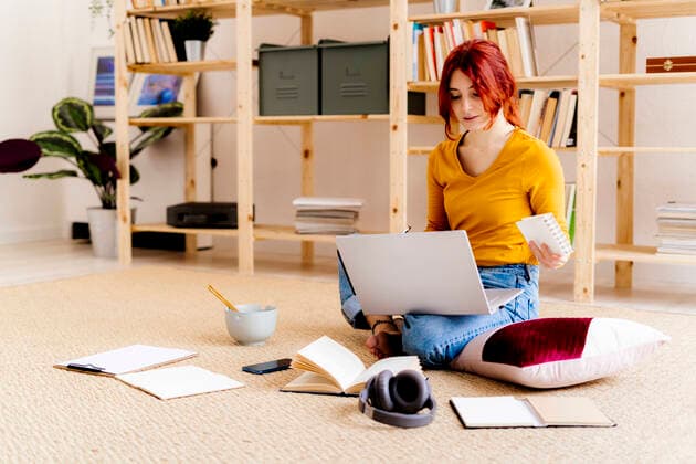Young woman using laptop while sitting against bookshelf at home model released Symbolfoto property released GIOF09882