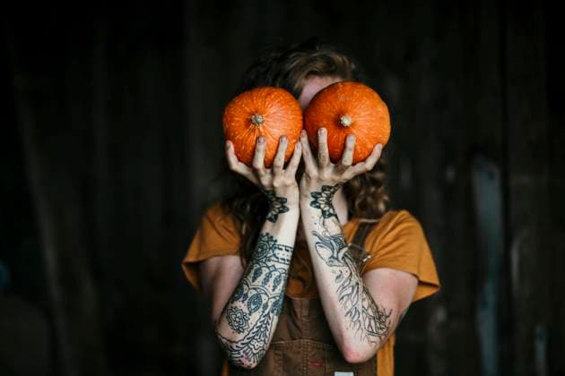 Woman covering face with red kuri squash while standing outdoors model released Symbolfoto property released MJRF00327