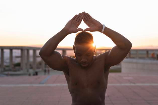 IMAGO Creative: Clickbait, Sport und Fitness Man with arms raised doing yoga while standing at park during sunset model released Symbolfoto PNAF00212