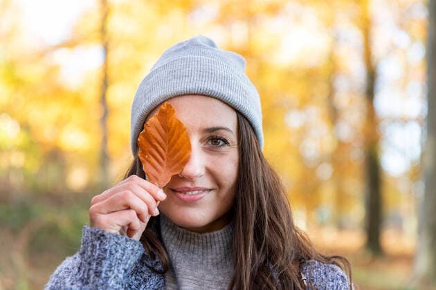 Beautiful woman covering eye with autumn leaf in Cannock Chase woodland model released Symbolfoto  WPEF03694