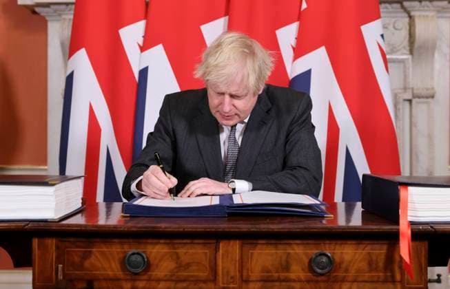 (201231) -- LONDON, Dec. 31, 2020 -- British Prime Minister Boris Johnson signs the post-Brexit trade deal at 10 Downing Street, in London, Britain, on Dec. 30, 2020. British lawmakers on Wednesday approved the post-Brexit trade deal between Britain and the European Union (EU) by a large majority, paving the way for an orderly Brexit when the transition period ends on Thursday. ( No 10 Downing Street Handout via Xinhua) BRITAIN-LONDON-PARLIAMENT-POST-BREXIT TRADE DEAL AndrewxParsons 