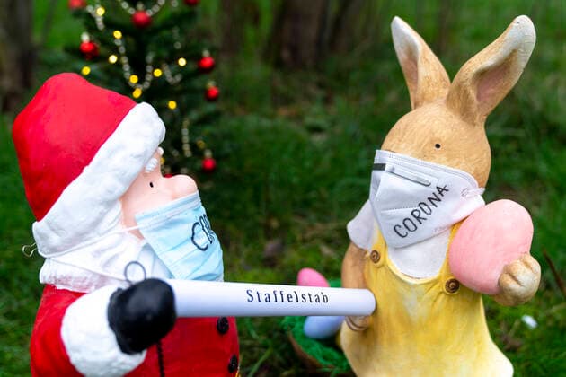 Symbolic photo baton handover of Santa Claus and Easter Bunny to the Corona Lockdown and protective measures Current, Sybolbild Santa Claus and Easter Bunny with mask Santa Claus symbolically passes the baton to the Easter Bunny Will the Corona protective measures or the lockdown extended until Easter Germany