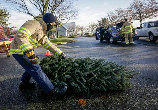 (210103) -- RICHMOND (CANADA), Jan. 3, 2021 -- A firefighter collects a Christmas tree at the annual Christmas tree chipping event in Richmond, British Columbia, Canada, on Jan. 3, 2021. Firefighters volunteered to help residents recycle their Christmas trees at the annual tree chipping event. (Photo by Xinhua) CANADA-RICHMOND-FIREFIGHTERS-CHRISTMAS TREE CHIPPING LiangxSen 