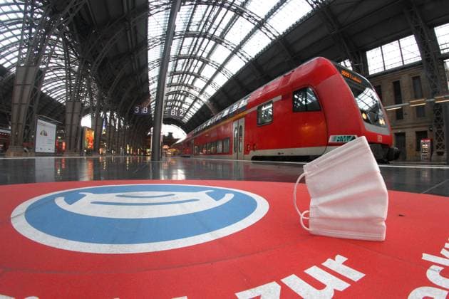 Worn mouth nose mask lies on the platform in front of a DB Deutsche Bahn regional express train at Frankfurt central station, Hesse, Germany