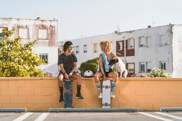IMAGO Creative, Urban Lifestyle IMAGO Creative, Jahreszeit Sommer, Sommer in der Stadt Friends with skateboard and dog talking while sitting on retaining wall in city model released Symbolfoto DAMF00555