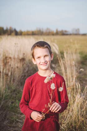 Smiling cute little boy with flower standing on field model released Symbolfoto EYAF01405