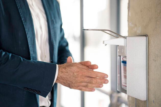 Businessman washing hands with sanitizer while standing at office model released Symbolfoto property released MOEF03486