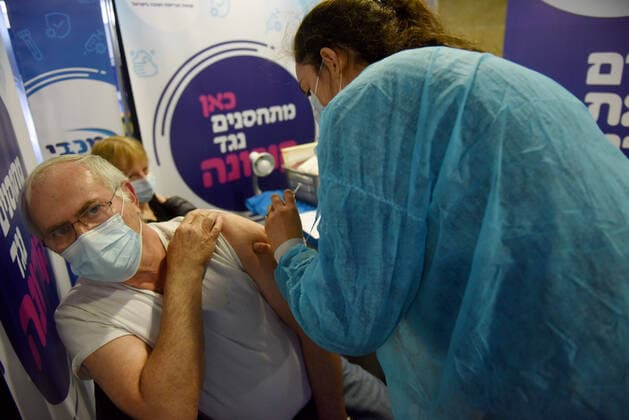 A man receives his second shot of the Pfizer- BioNTech COVID-19 vaccine in an Israeli vaccination center in Jerusalem, on Tuesday, January 12, 2021. Israel will expand the vaccination drive inoculating teachers and people over 50 years on Wednesday.  JER2021011220 DEBBIExHILL