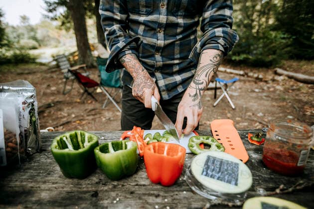 Creative Highlights Symbolbilder Man with tattoos chops vegetables on wood table while camping in woods Vanceboro, ME, United States CR_SSNF210115C-617238-01 ,model released, Symbolfoto