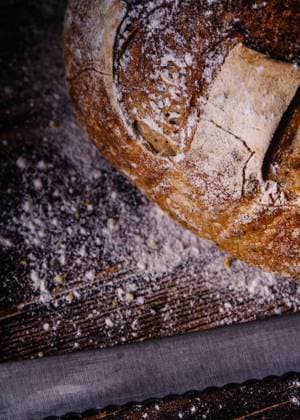 IMAGO Creative: Clickbait, Rezepte und Kochen Delicious bread with crust covered in flour placed on napkin near knife on wooden table in bakery Copyright: xAngelxSantamariax Model Released