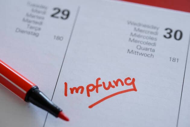 Symbol photo Entry of the Corona vaccination in the diary Symbol photo, entry and note of the vaccination date for a Corona vaccination with a red pen in the current daily diary 2021 Germany
