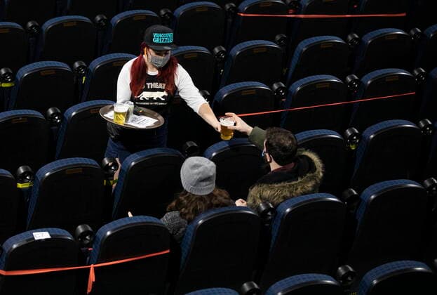 January 23, 2021, Vancouver, BC, Canada: A Rio Theatre server brings drinks to customers as they watch the Canucks take on the Canadiens in NHL action show on the theatre s screen during its first day open as a sports bar in Vancouver, Saturday, Jan. 23, 2021. The independent movie theatre, which has been closed due to provincial public health restrictions, is now open as a sports bar. Vancouver Canada  - ZUMAc35_ 20210123_zaf_c35_051 Copyright: xMarissaxTielx