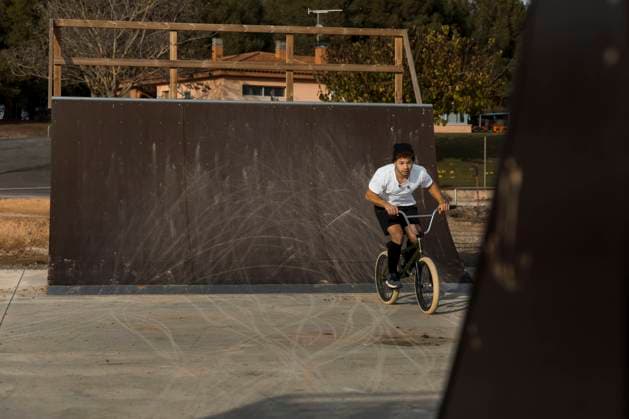 Young man cycling by ramp at bike park model released Symbolfoto ACPF01017