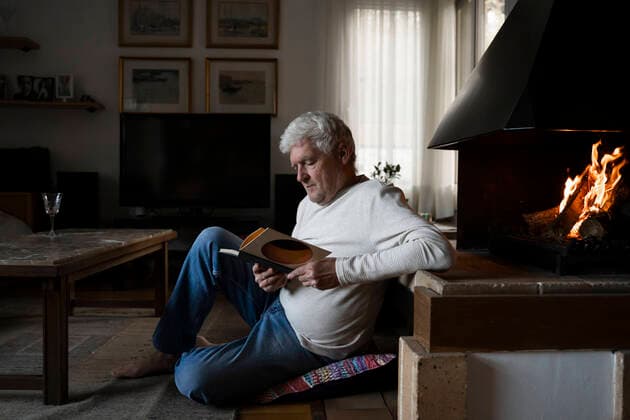 IMAGO Creative: Momentaufnahmen IMAGO Creative: Kulturelle Folgen der Pandemie: Gesundheitsbewußtsein und Alleinsein Senior man reading book while sitting on floor at home model released Symbolfoto property released AFVF07908