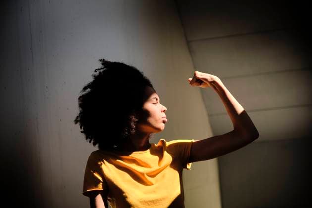 Young woman showing muscles while standing against wall model released Symbolfoto AODF00040