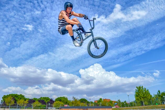 Carefree man with bicycle jumping against blue sky at bike park model released Symbolfoto property released GGGF00784