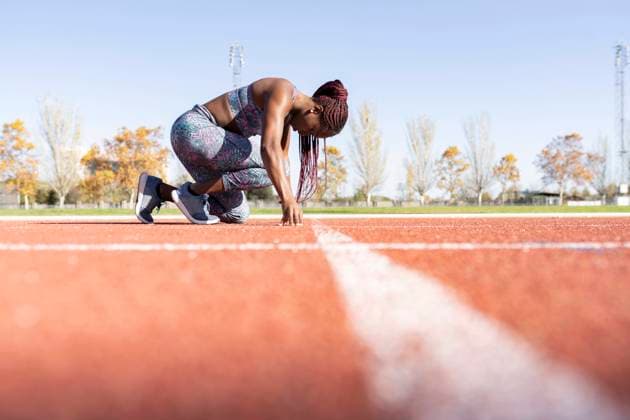 IMAGO Creative: 2021 Favoriten Female athlete in ready position on running track during sunny day model released Symbolfoto JCCMF00526