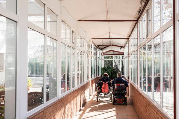 IMAGO Creative: NGO, Rehabilitation und Gesundheitswesen Disabled male and female on wheelchair in corridor at nursing home model released Symbolfoto property released LJF01996