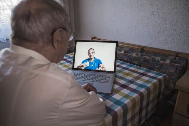 Male doctor consulting senior man on laptop at home model released Symbolfoto property released UUF22251