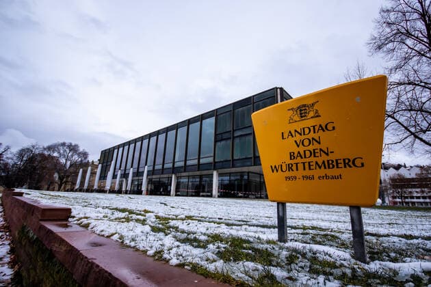 Stuttgart Landtag Baden-Wuerttemberg, Landtagswahlen 2021, 25.01.2021 Landtag von Baden-Wuerttemberg, 1959-1961 erbaut, gelbes Schild, Wiese, Schnee, Landtagsgebaeude im Hintergrund, Das Landtagsgebaeude von Baden-Wuerttemberg wurde 1961 erbaut und war der erste Parlamentsneubau nach dem Zweiten Weltkrieg in Deutschland. Der Architekt Kurt Viertel aus Mainz entwarf das quadratische Gebaeude mit einer Hoehe von 12 Metern. Während einer Generalsanierung zwischen 2013 und 2016 und Umbauphase fanden Plenarsitzungen im Kunstgebaeude am Schlossplatz statt. Eine Glasfront sorgt seither fuer Tageslicht auch im Innern des Gebaudes. Landtagswahlen 2021: Am 14. Maerz 2021 wird in Baden-Wuerttemberg ein neuer Landtag gewaehlt. Zum 30. April 2021 en Copyright: xTabeaxGuenzler Eibner-Pressefotox LBW