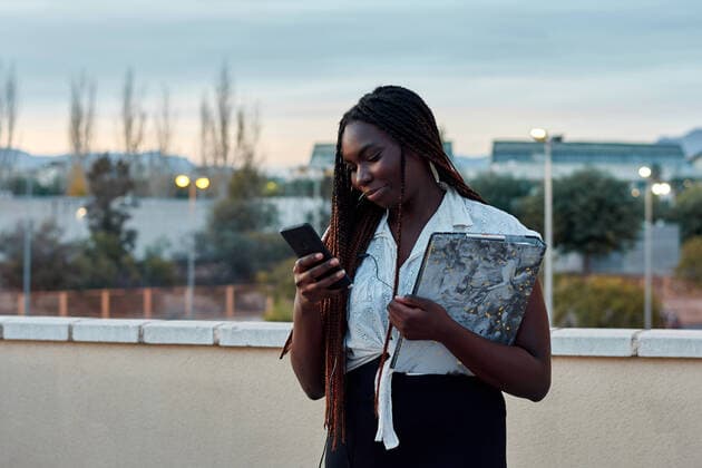 Young student with black skin is looking at her phone on a campus Sant Vicent del Raspeig, Comunitat Valenciana, Spain CR_CRBL210127-618056-01 ,model released, Symbolfoto