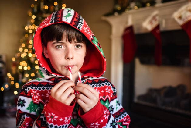 Cute boy in festive pajamas eating a candy cane at Christmas time. Kingston, ON, Canada CR_DOHO210113K-607764-01 ,model released, Symbolfoto