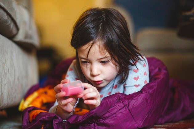 A little girl lays on floor in sleeping bag studying a tube of liquid Columbus, OH, United States CR_RETI210114-575732-01 ,model released, Symbolfoto