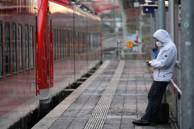 DB , Deutsch Bahn , Railway , Train , A young men with Safety Mask FFP2 and Mobile Phone is seen at Nurnberg Steinbuhl Station during the Hard Lockdown of the Covid 19 Coronavirus Pandemie in Nurnberg Nuremberg , Bayern , Deutschland . February 03 , 2021.