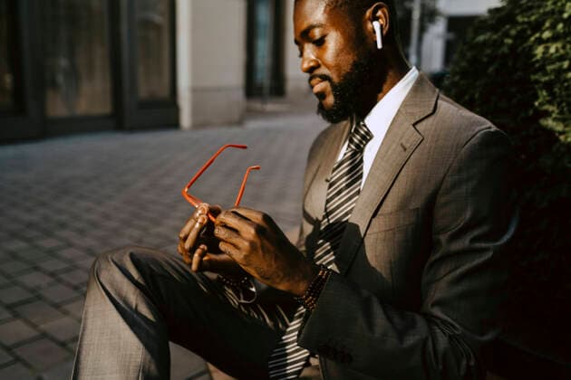 Creative Highlights Symbolbilder Male entrepreneur looking at eyeglasses while sitting on footpath Germany, Berlin, model released Copyright: xMaskotx , MA84234