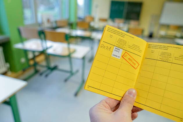 Symbolic image school and classroom in lockdown Symbolic photo of a vaccination certificate with vaccination stamp against the coronavirus with classroom of a school in the background When will teachers and students be vaccinated Germany