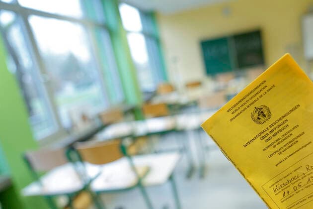 Symbol image school and classroom in lockdown Symbol photo of a vaccination certificate with classroom of a school in the background Teachers are currently in risk group three and later in vaccination Germany