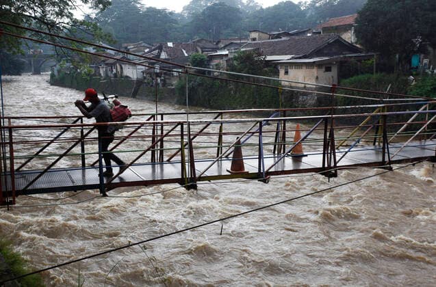 IMAGO Nature: Unsere Erde, Klimawandel, Überschwemmungen News Bilder des Tages Indonesia s Weather A Man walk on the bridge during the Ciliwung river water level rises caused by High-intensity rain in the Bogor region, on February 9, 2021 in Bogor, West Java. Based on data the Indonesian Meteorology, Climatology and Geophysics Agency (BMKG) the La Nina climate anomaly is developing in the Pacific Ocean, its impact on Indonesia can cause extreme weather with high rainfall and result in hydrometerological disasters such as floods and landslides. A number of areas in Jakarta were flooded. (Photo by Adrian INA Photo Agency) 