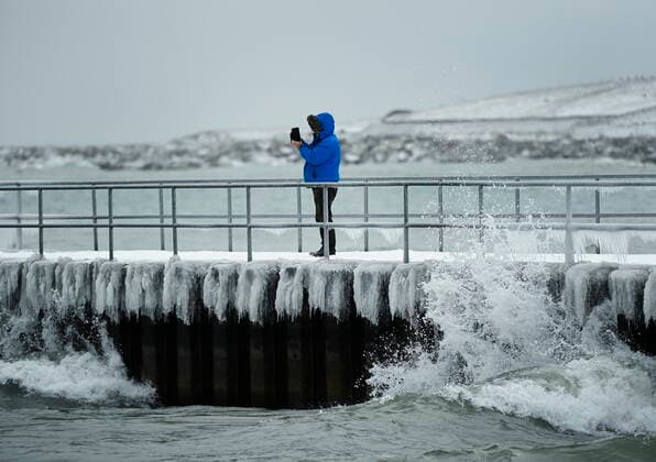 February 12, 2021, Toronto, on, Canada: A person photographs a surfer in the frigid ice cold waters of Lake Ontario during the COVID-19 pandemic in Toronto on Friday, February 12, 2021. Toronto Canada  - ZUMAc35_ 20210212_zaf_c35_035 Copyright: xNathanxDenettex