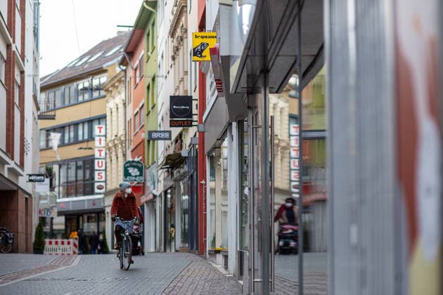 The Bonn city center on 16 02 2021 Bonn city center on 16 02 2021 Photo Almost empty shopping street, here the Acherstraße, due to the Corona pandemic all shops will be closed until probably the end of February 2021 Photo A woman rides her bike through the Acherstraße Bonn city center North Rhine Westphalia Germany