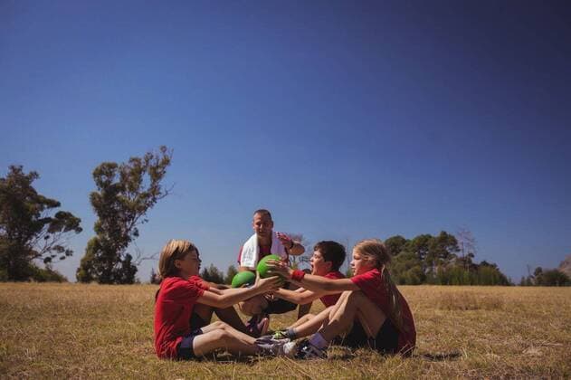 IMAGO Creative: Lokalhelden - Jugendsportbildung Trainer instructing kids while exercising in the boot camp Trainer instructing kids while exercising in the boot camp on a sunny day, model released, , property released, Cape Town, South Africa, 16.03.2017, 1000431.jpg, boot, camp, boot camp, park, sky, grass, tree, summer, sunny, sportswear, towel, sneakers, athlete, athletic, trainer, trainee, coach, instructor, sport, sports, ball, ball sit up, sitting, holding, exercise, exercising, training, practicing, instructing, instruction, guidance, healthy lifestyle, childhood, together, fit, fitness, wellness, wellbeing, active, activity, healthy, strength, stamina, energy, effort, endurance, recreation, challenge, competition Outdoors,Day