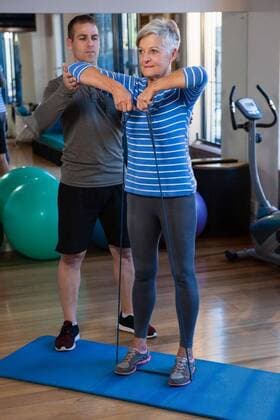 Male physiotherapist helping patient in performing exercise with resistance band Male physiotherapist helping patient in performing exercise with resistance band in clinic, model released, , property released, Cape Town, South Africa, 2017-04-22T23:00:00.000Z, 1052518.jpg, physio, physiotherapy, physiotherapist, practitioner, orthopedic, physical therapy, physical therapist, therapy, clinic, hospital, health service, healthcare, bodycare, healthcare and medicine, sportswear, training, routine, healthy lifestyle, wellness, wellbeing, active, activity, fit, fitness, health, healthy, physical, determination, exercise, exercising, workout, working out, patient, helping, assistance, stretching, holding, resistance band, yoga mat, exercise ball,