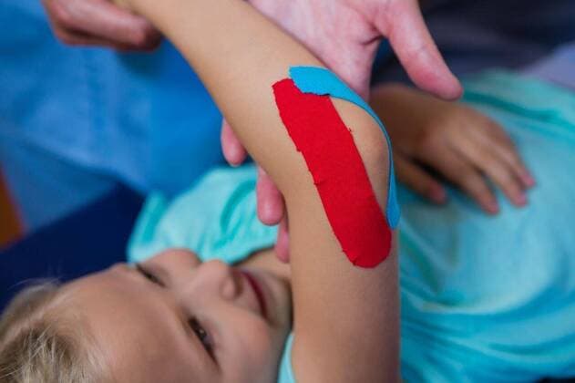 Physiotherapist sticking tape on girl patient Physiotherapist sticking tape on girl patient in hospital, model released, , property released, Cape Town, South Africa, 2017-04-22T23:00:00.000Z, 1052774.jpg, medical, clinic, hospital, physio, physiotherapy, physiotherapist, orthopedic, physical therapy, therapy, physical therapist, doctor, specialist, profession, professional, patient, casual clothing, sticking, assisting, kinesiotape, kinesiotaping, elbow, illness, assistance, treatment, medical treatment, cure, recovery, health, health service, bodycare, healthcare, healthcare and medicine, expertise, childhood Child, Girl, Female, Caucasian, 50s, Mature Adult, Woman, 6-7 Years, Girls, Caucasian Ethnicity, 50-54 Years, Mature Women Indoors