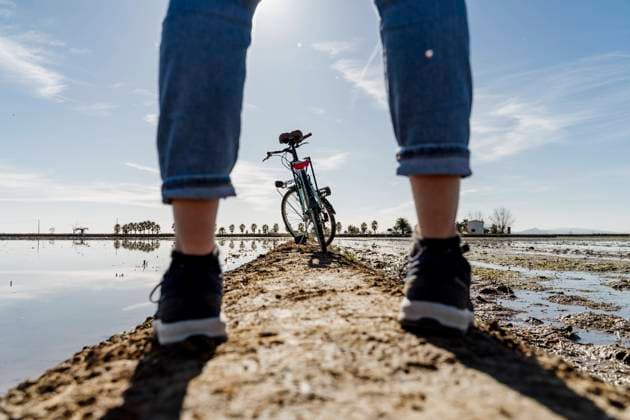 Bicycle seen through legs of woman standing on footpath at Ebro s Delta during sunny day, Spain model released Symbolfoto AFVF08062