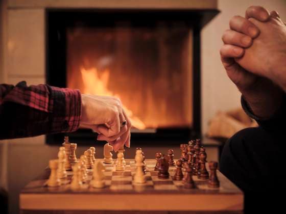 IMAGO Creative: Herbst, Gemütliches Zuhause Couple playing chess by fireplace at home during winter model released Symbolfoto property released DIKF00551