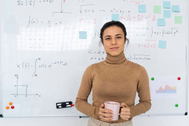 Female student holding coffee cup while standing against whiteboard at home model released Symbolfoto property released GIOF10666